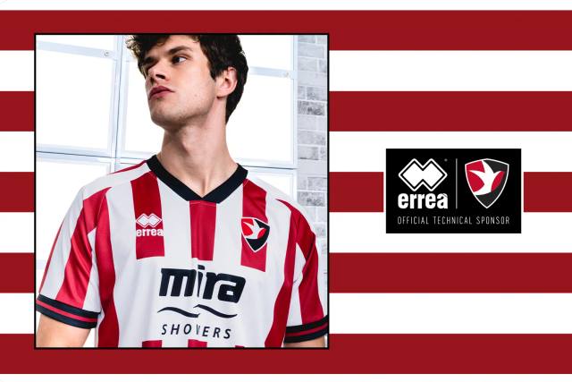 A model presents the Erreà Cheltenham Town FC 2024/25 home shirt, featuring red and white vertical stripes.