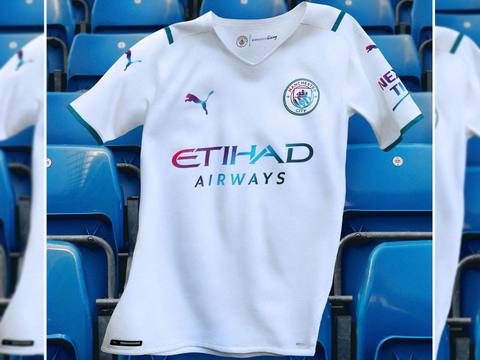 The Manchester City 2021/22 away shirt, featuring iridescent details, draped over blue stadium seats.