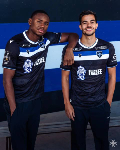 AJ Auxerre players presenting the new Macron away shirt, featuring a black design with a blue and white chest band.