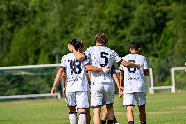Three Bologna FC players seen from behind wearing the white away shirt during a match.