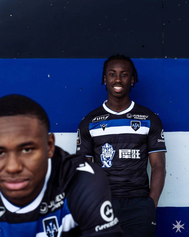 AJ Auxerre player posing in the club's black, blue and white away shirt.
