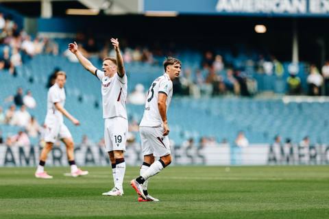 Bologna players on the pitch wearing their white 2024/25 away kit.