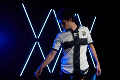 A model presents the Parma Calcio 2022/23 home shirt with its iconic black cross design.