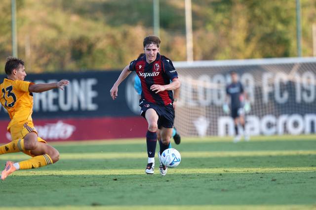 A Bologna FC player on the pitch wearing the club's home shirt with Saputo sponsor logo