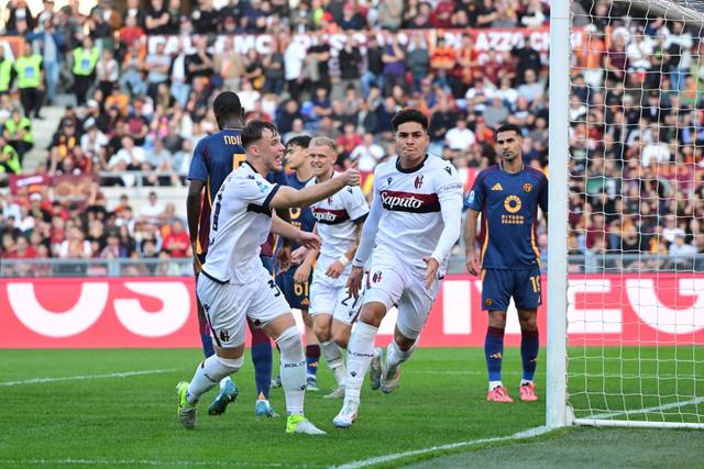 Bologna FC 1909 players celebrate on the pitch wearing their white away kit.