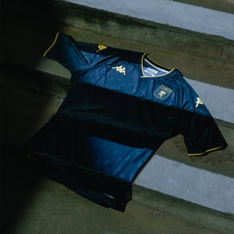 The Genoa CFC 2024/25 third shirt by Kappa, in dark blue with gold details, laid on concrete steps.