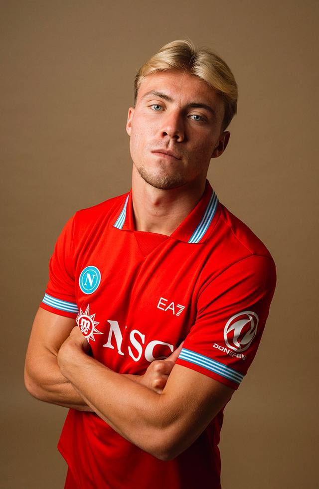A studio portrait of a player wearing the SSC Napoli red third shirt with white and blue details.