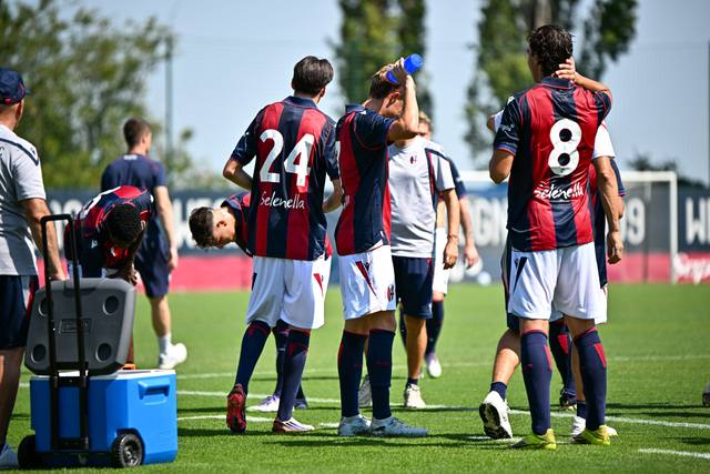Bologna FC players wearing their red and blue striped home kit during a training session.