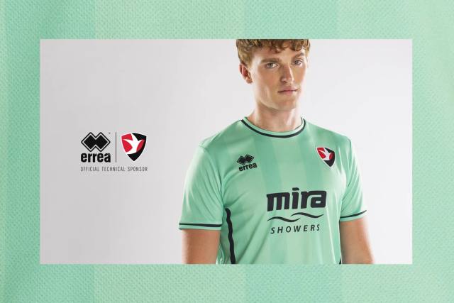 A model presents the Cheltenham Town FC 2023/24 away shirt by Erreà.