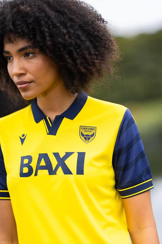 A model wears the yellow and navy Oxford United FC home shirt.