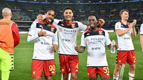 Genoa players celebrate on the pitch wearing their white 2023/24 away kit.
