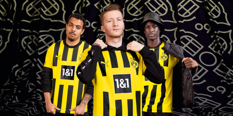 Borussia Dortmund players wear the club's 2022/23 home shirt featuring vertical black stripes on a yellow base.