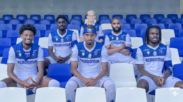 AJ Auxerre players pose on stadium seats wearing the 2023/24 home kit.