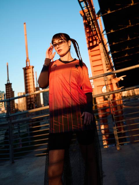 A model wearing the Genoa CFC x Kappa FuturFestival special edition football shirt with a red-to-black gradient pattern.