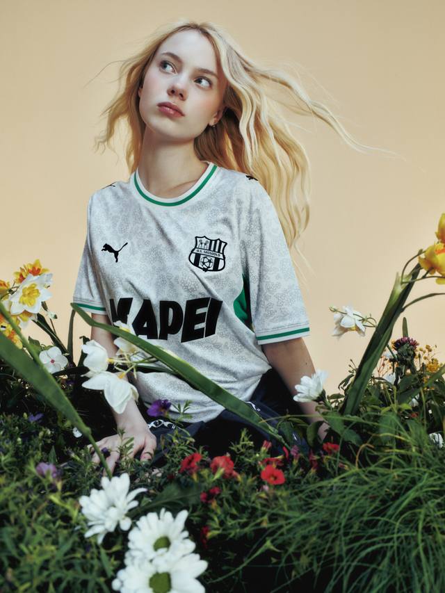A model wears the Puma U.S. Sassuolo Calcio away shirt, featuring a patterned white base with green accents.