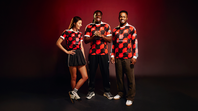Models present the Fulham FC away shirt featuring a red and black checkered pattern.