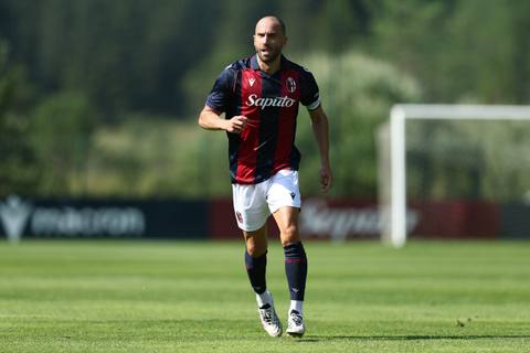 A Bologna FC player on the pitch wearing the red and blue home shirt with the Saputo sponsor.