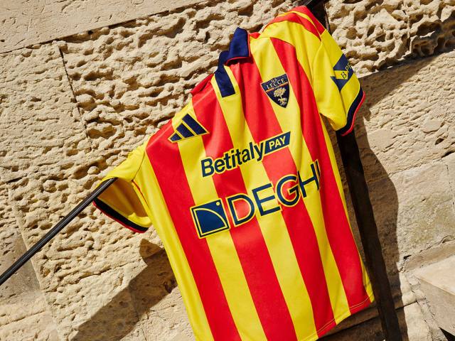 The U.S. Lecce home shirt featuring its classic red and yellow vertical stripes, displayed on location.