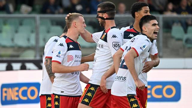 Genoa players celebrate in their white 2023/24 away shirt with red and blue chest detailing